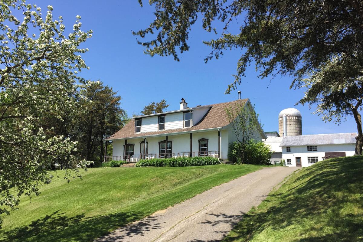 A two-story house with a porch, a silo, and a well-maintained lawn.