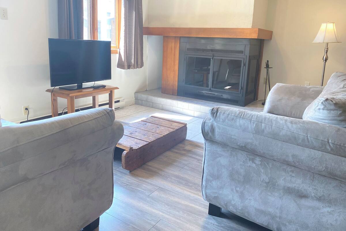 A living room with a fireplace, a television on a wooden stand, and two sofas.