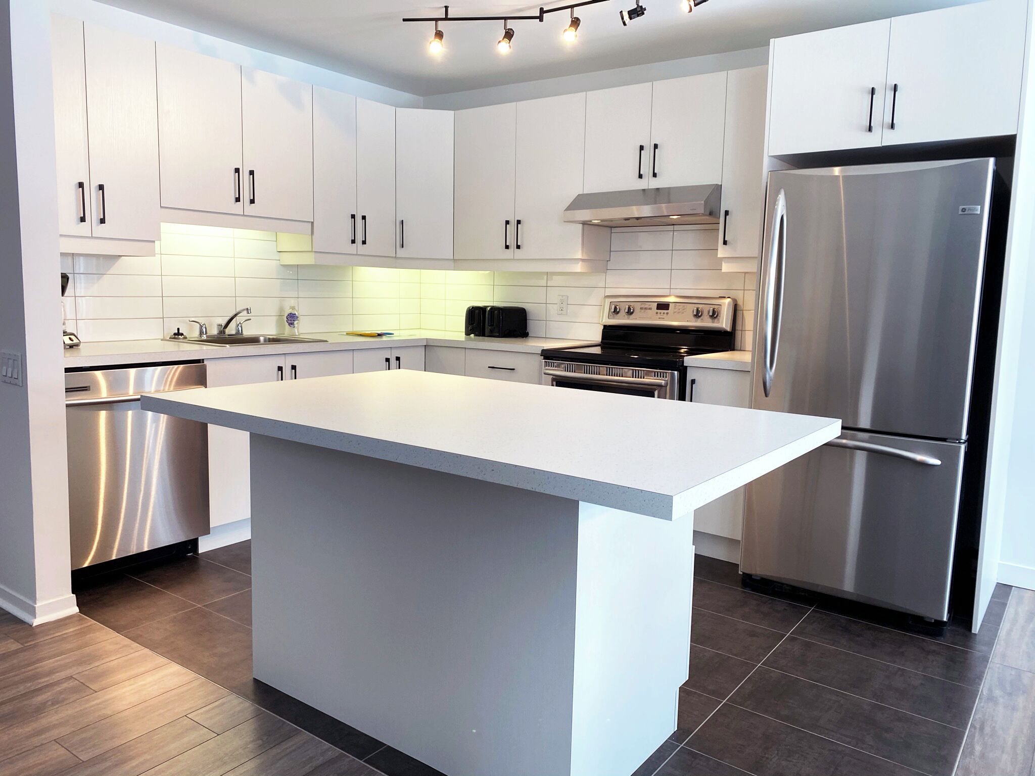 Una cocina moderna con armarios blancos, electrodomésticos de acero inoxidable y una isla grande.