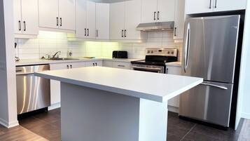 Una cocina moderna con armarios blancos, electrodomésticos de acero inoxidable y una isla grande.