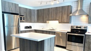 Una cocina moderna con una isla central, electrodomésticos de acero inoxidable y armarios de madera.