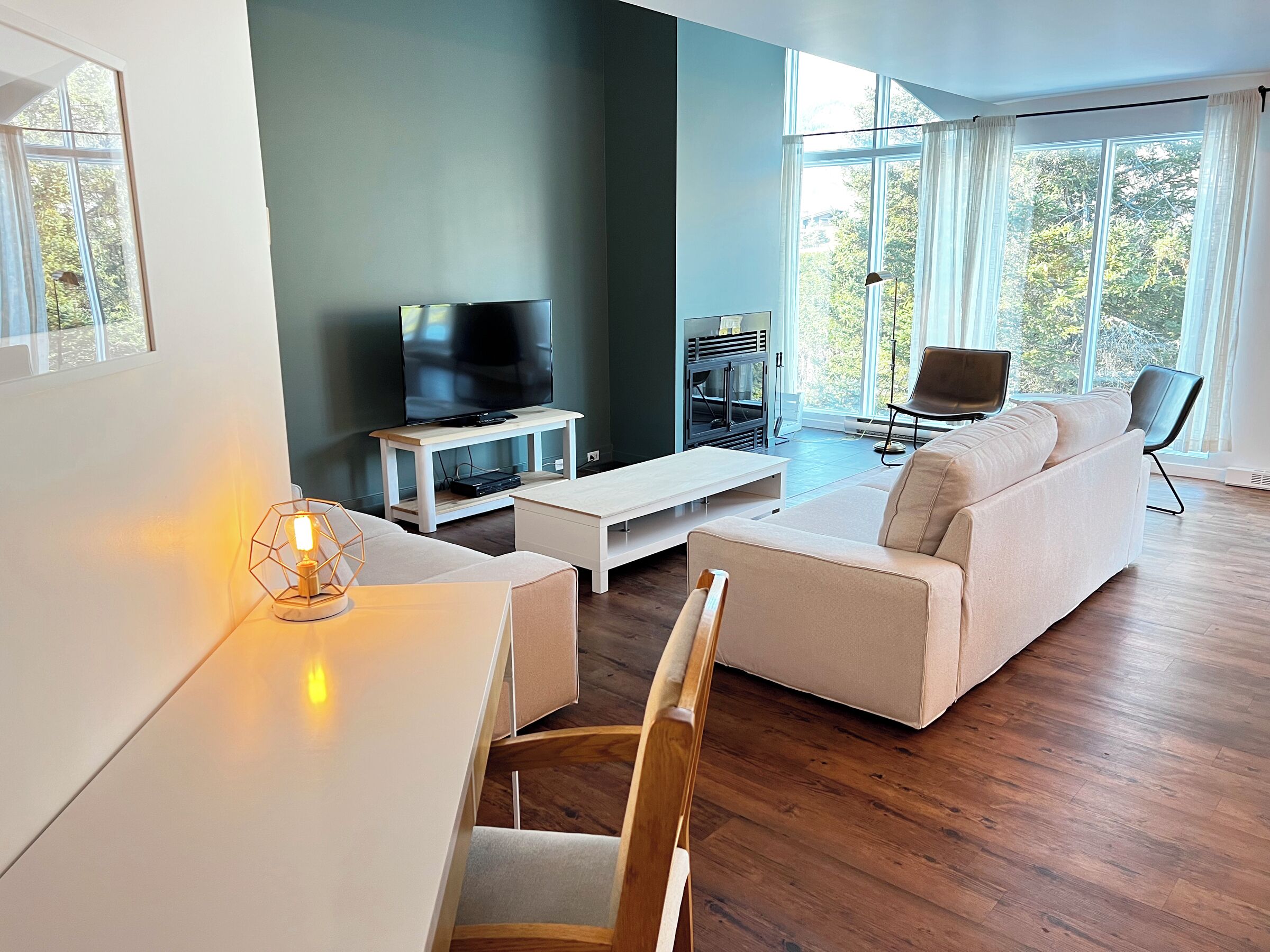 Una sala de estar moderna con una televisión de pantalla plana, un sofá, una mesa de centro y una mesa de comedor.