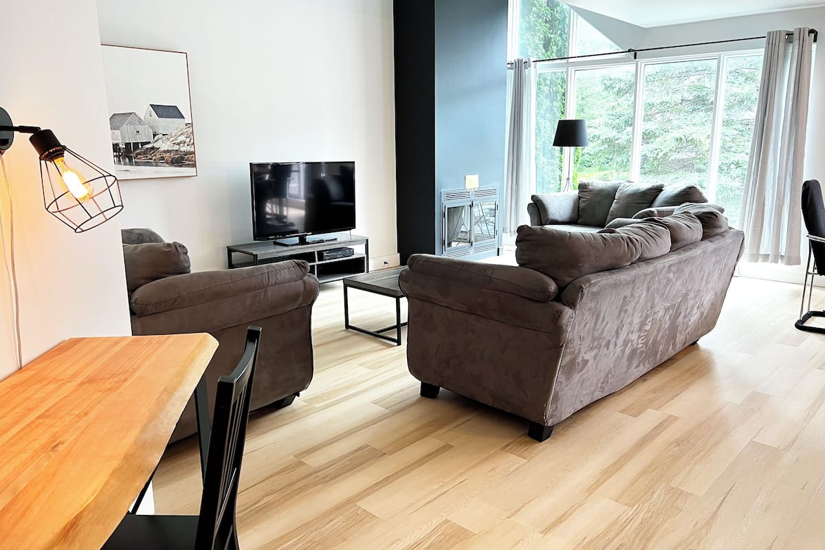 A modern living room with a sofa, a TV, and a dining area.