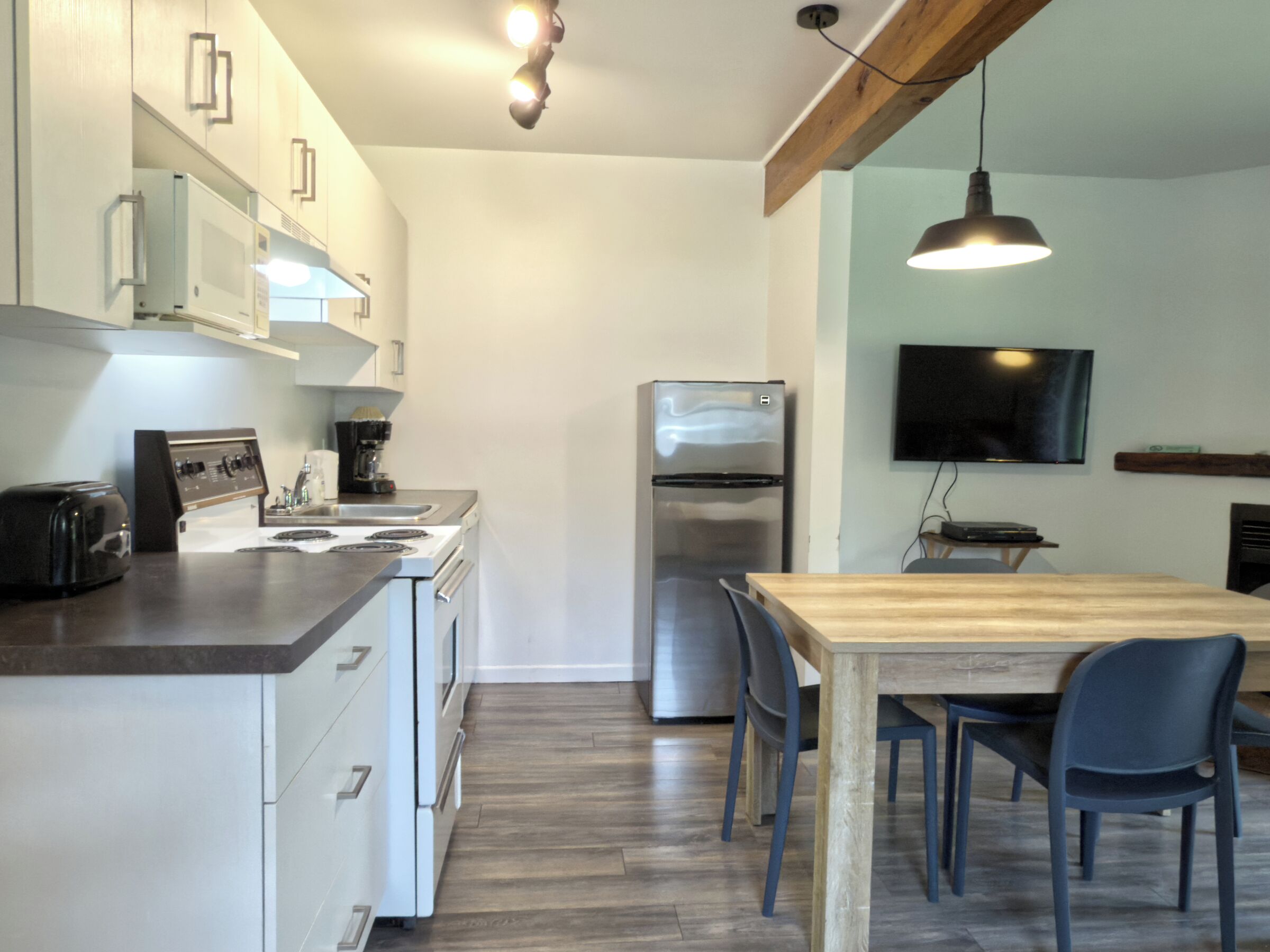 Een moderne keuken met een houten tafel en stoelen, een koelkast en een magnetron.
