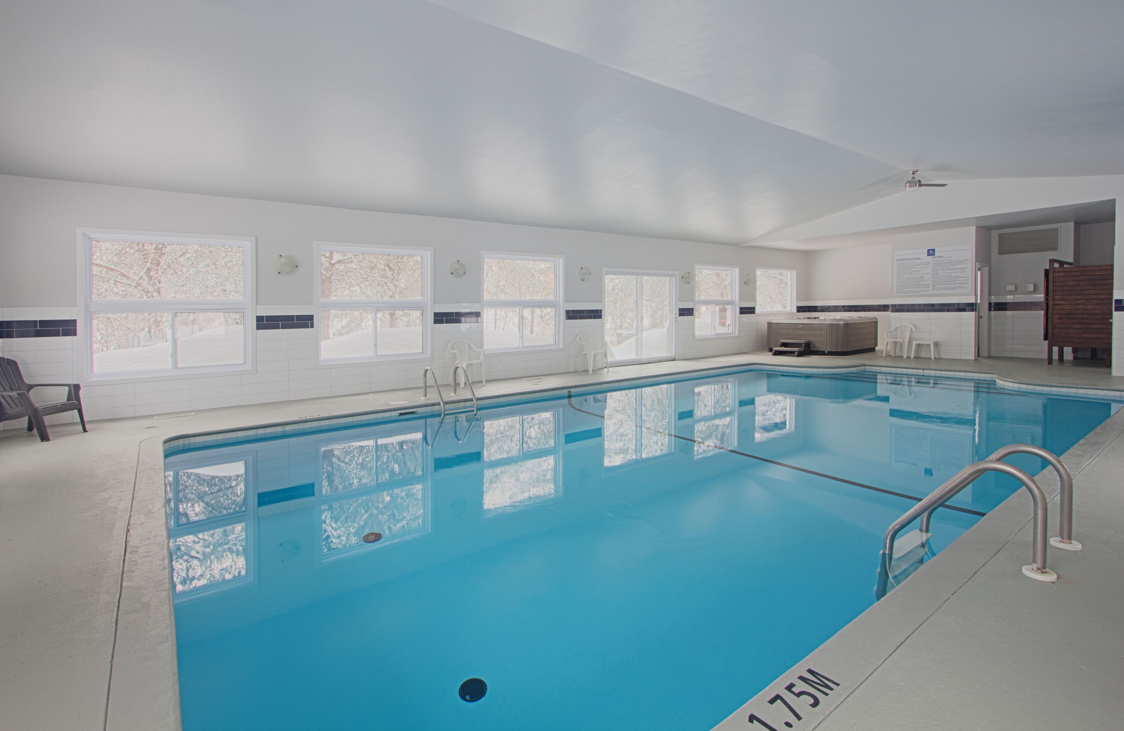A swimming pool with clear blue water, a lifeguard chair, and a sauna area.