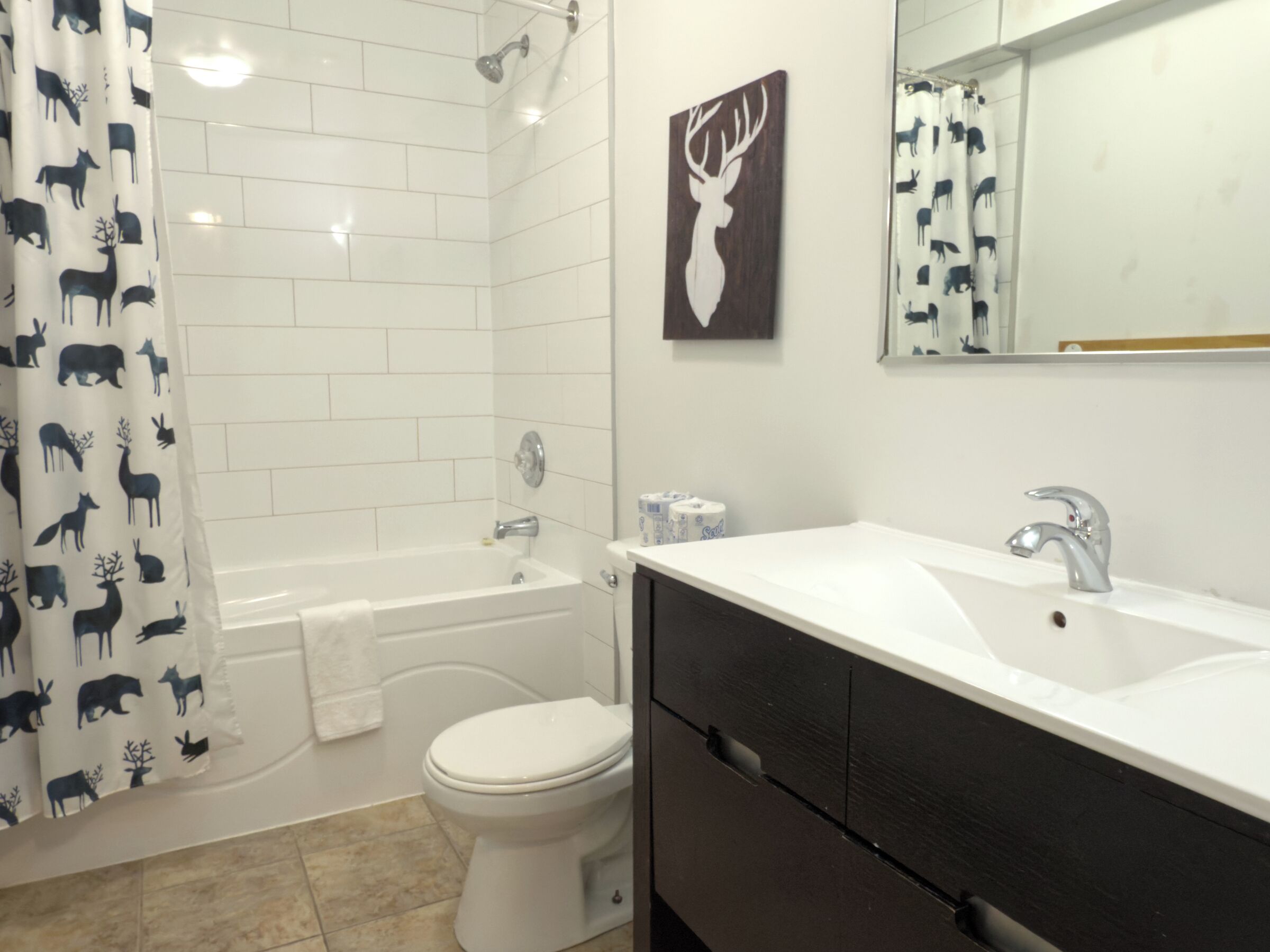 A bathroom with a white bathtub, a white toilet, and a sink with a dark cabinet.
