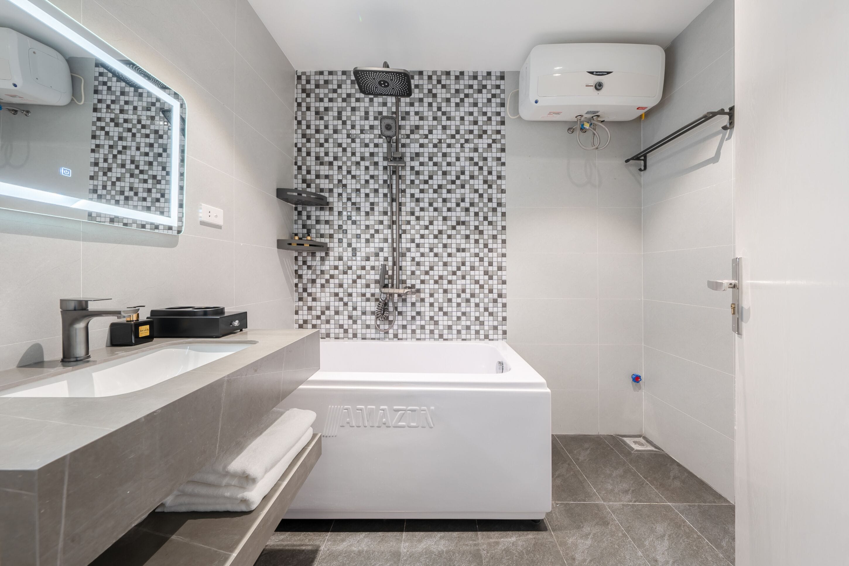 A modern bathroom with a white bathtub, a large mirror, and a tiled shower wall.