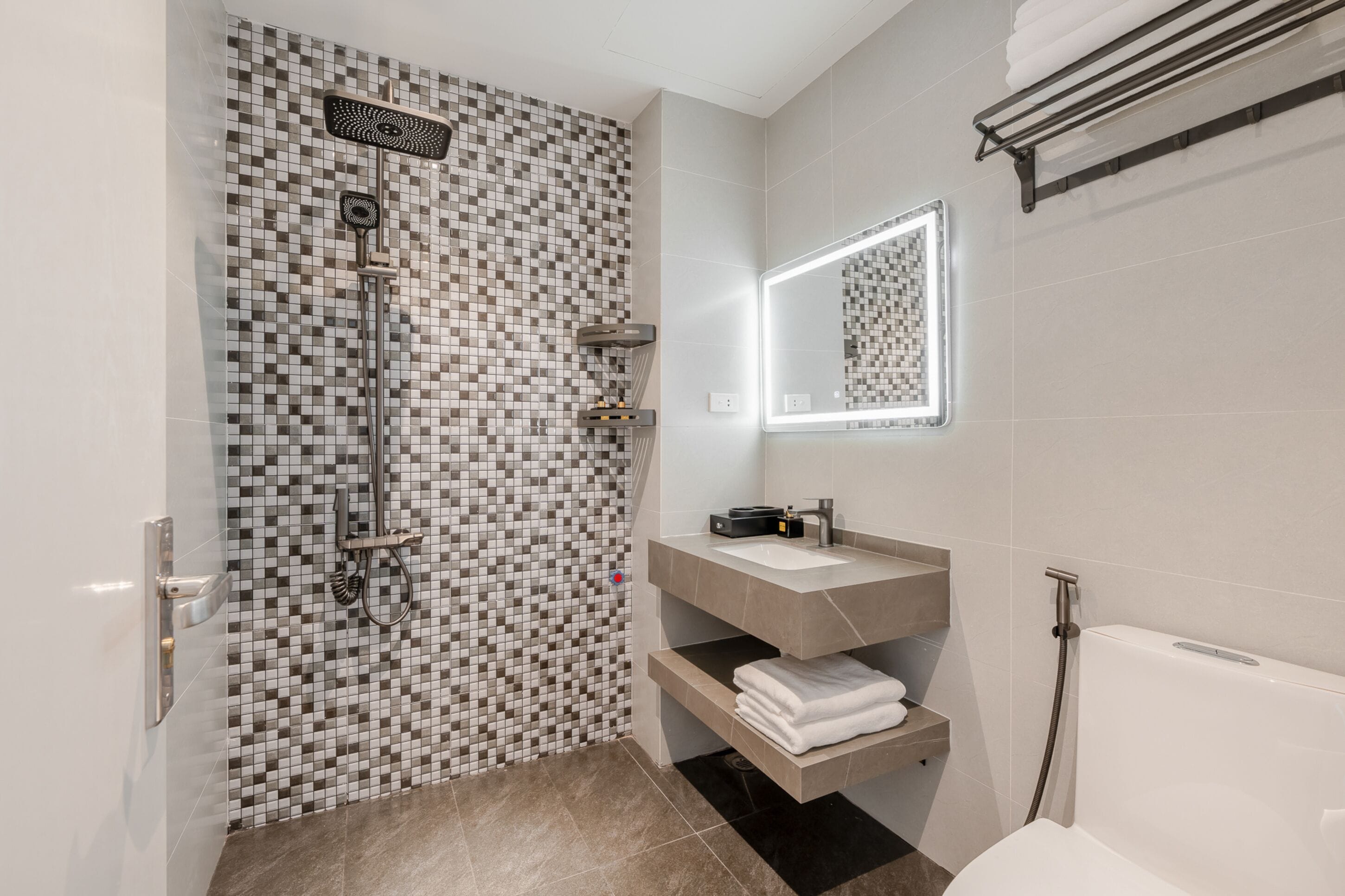 A modern bathroom with a shower, a sink, a mirror, and a toilet.