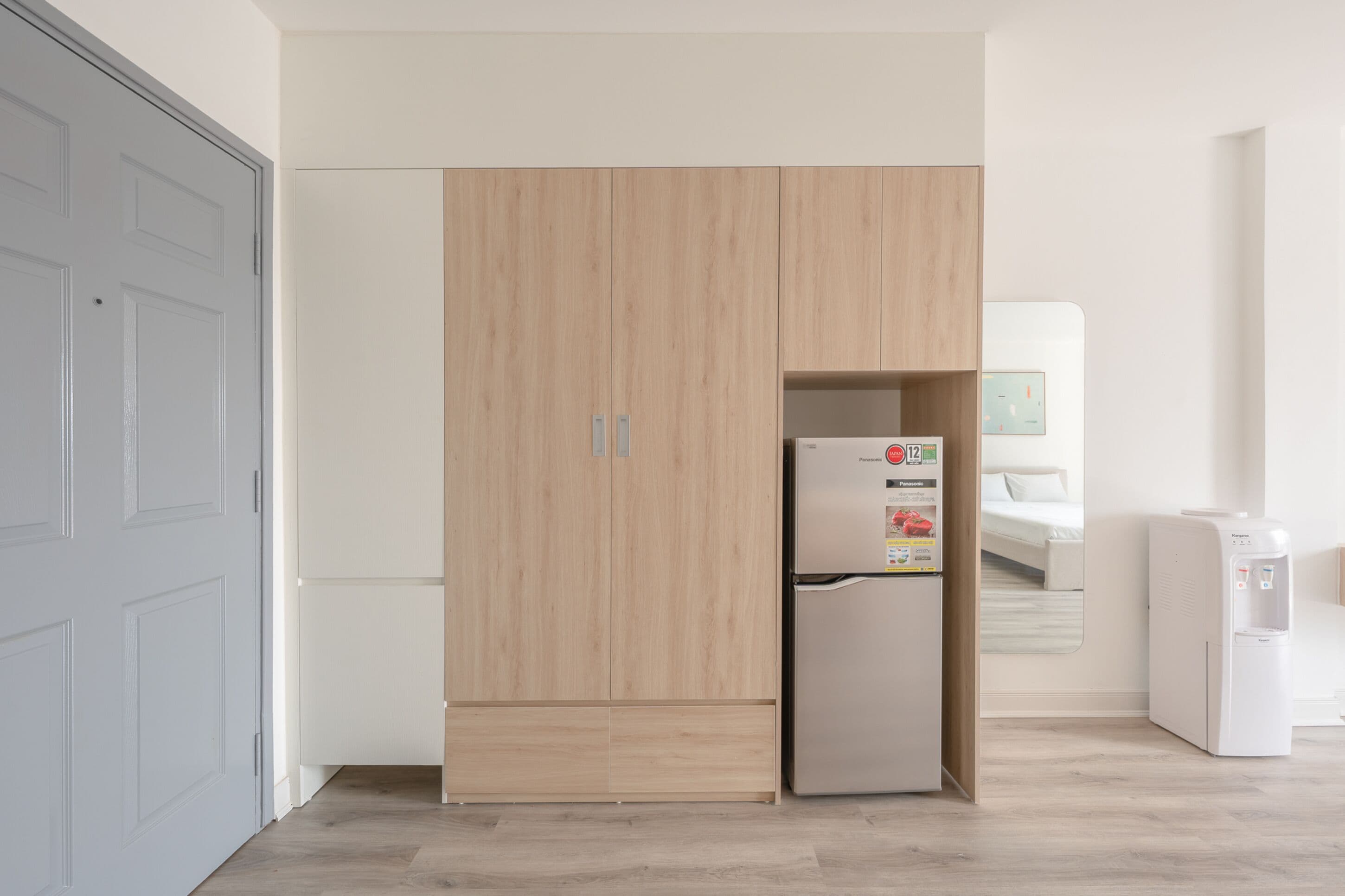 A modern kitchen with a built-in refrigerator, a water dispenser, and a wooden cabinet.