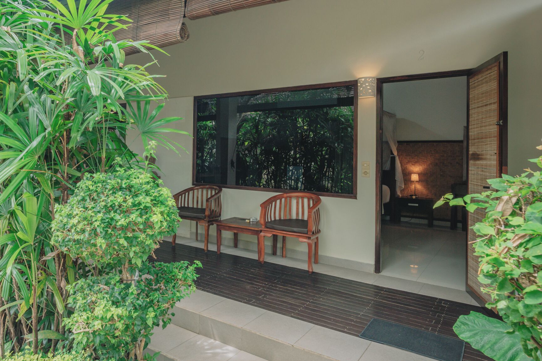 A room with a large window, two wooden chairs, and a small table.