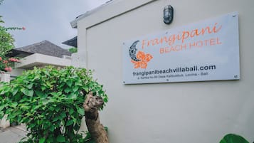 Letrero del Hotel Frangipani Beach con una dirección web y detalles de ubicación.