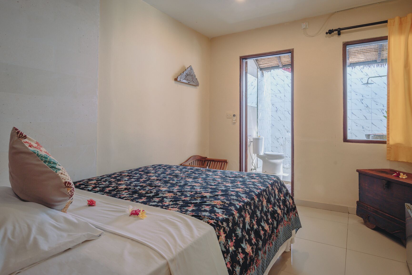 Une chambre à coucher avec un lit, une table de chevet en bois, une fenêtre avec des rideaux et une vue sur l’extérieur.