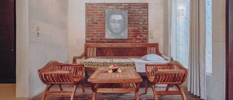A bedroom with a wooden bed, a brick wall mural, a wooden table, and two wooden chairs.