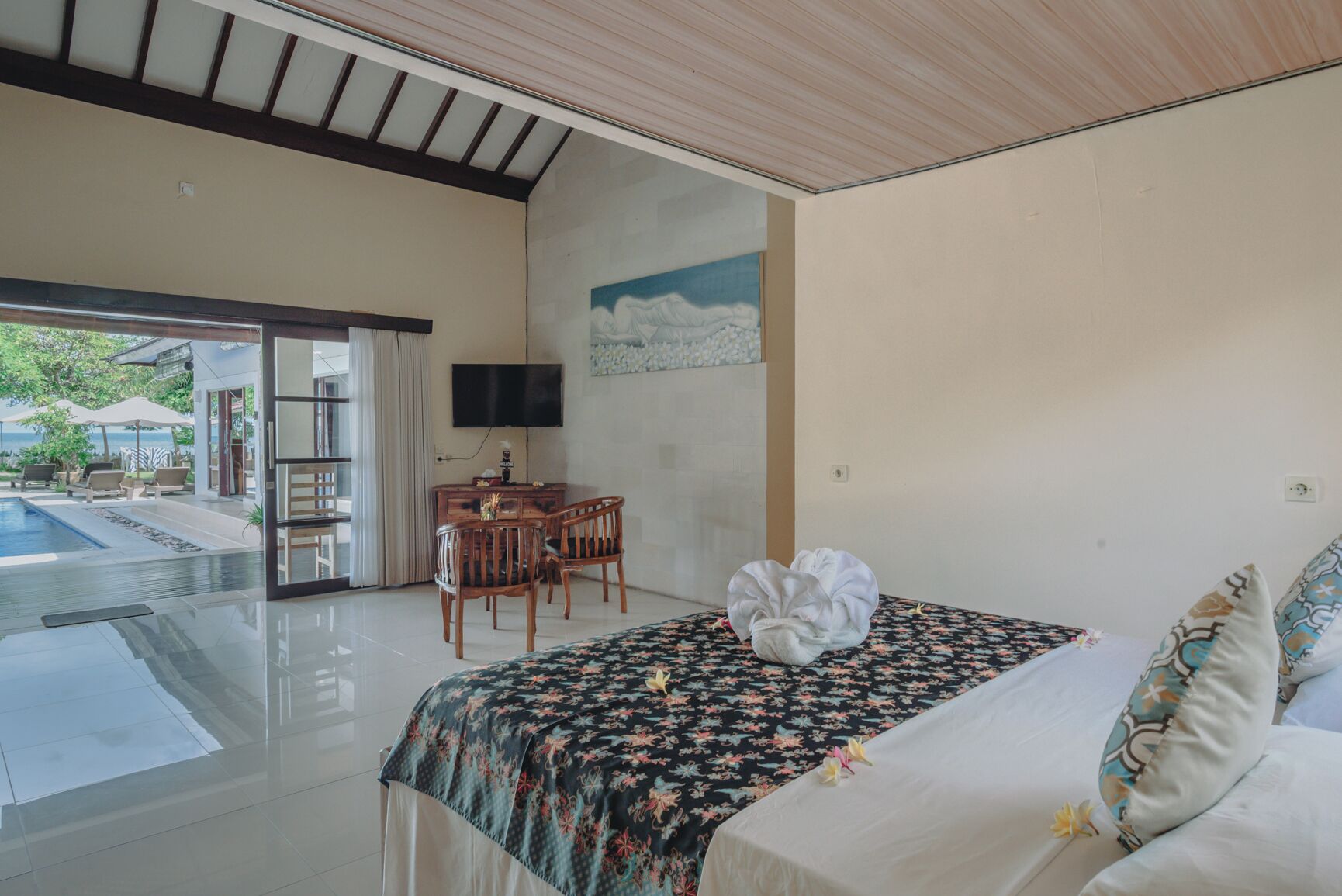 Une chambre à coucher avec un lit, un bureau et une chaise. Il y a un téléviseur accroché au mur et une fenêtre donnant sur l’extérieur.