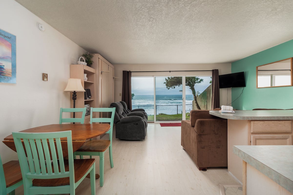 A modern living room with a dining area, a sofa, and a television.