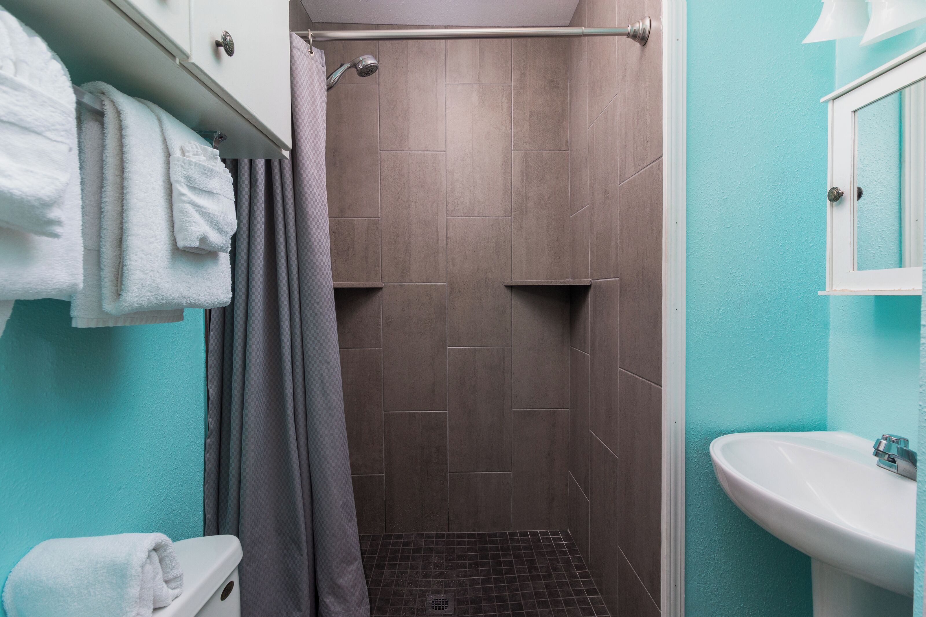 Un baño con ducha, lavamanos y toallas.