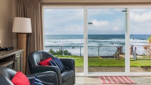 A room with a view of the ocean, a sliding glass door, a leather chair, a lamp, and a small table. - Ocean Terrace Condominiums (Lincoln City)