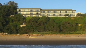 A multi-story building with a flat roof, located on a hillside overlooking a beach. - Ocean Terrace Condominiums (Lincoln City)