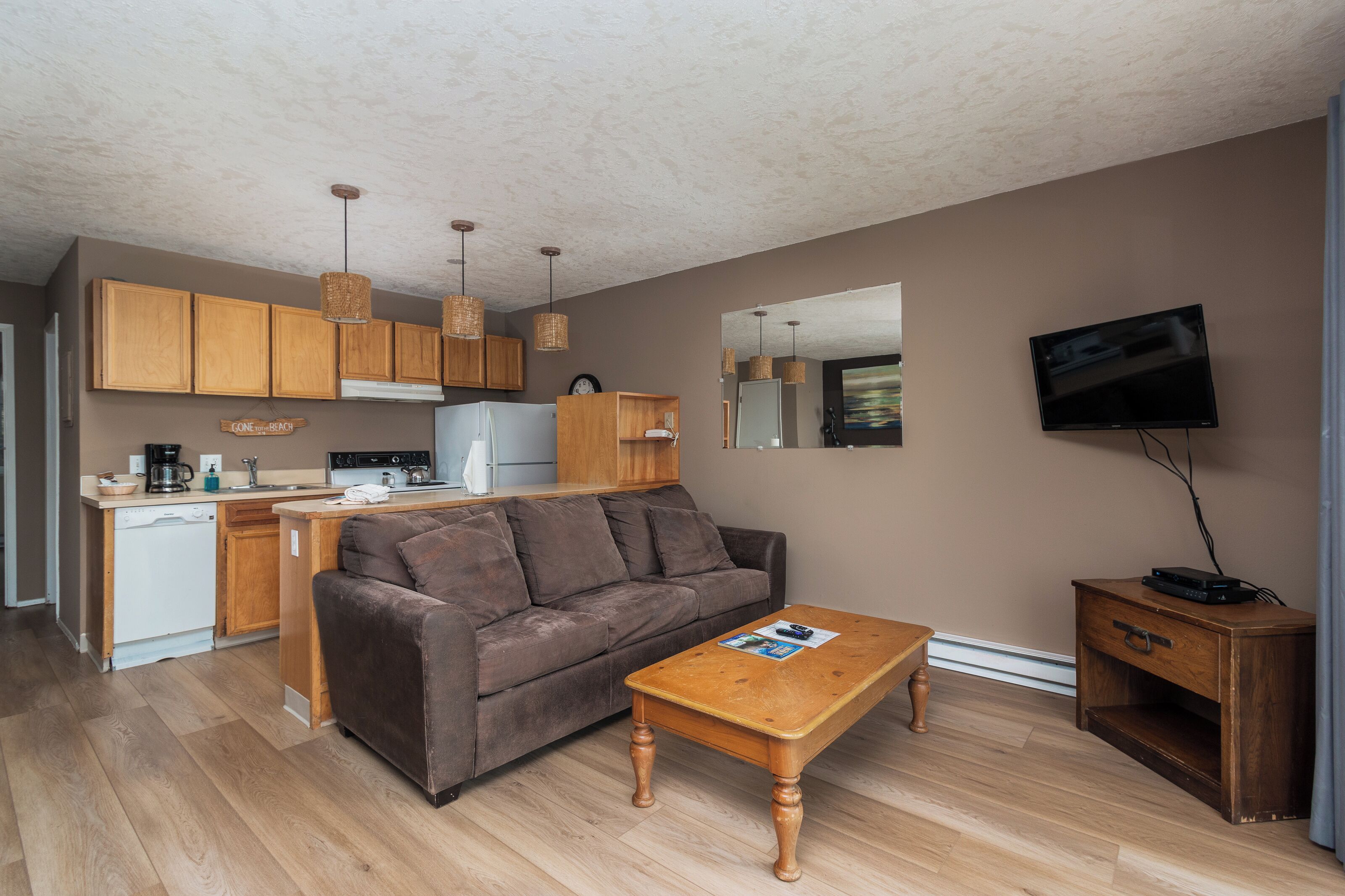 A compact living space with a kitchenette, a sofa, a coffee table, and a TV.