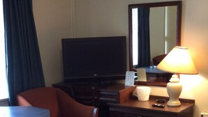 A hotel room with a TV, a desk, a chair, a lamp, and two beds. - Tidewater Motel (Hayes)
