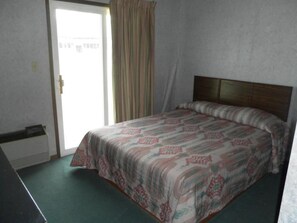 Un dormitorio con cama, escritorio y ventana con cortinas.