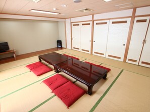 A tatami mat room with a wooden table and red cushions.
