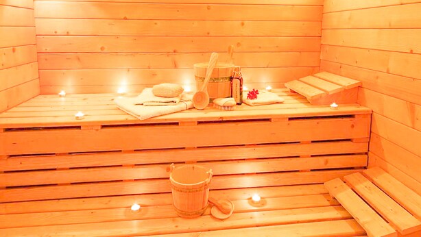 A wooden sauna with benches, a bucket, a bottle, and a towel. - Hotel Livemax Chitose (Chitose)