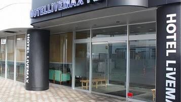 Hotel LIVEMAX con fachada de vidrio, un pilar negro y suelo de baldosas.