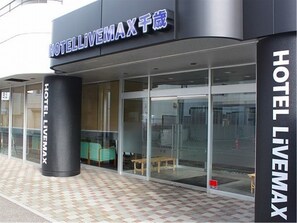 Hotel LIVEMAX with a glass facade, a black pillar, and a tiled floor.
