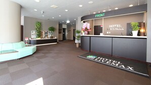 A hotel reception area with a reception desk, a light blue sofa, and a reception counter with a sign that reads "HOTEL LIVEMAX". - Hotel Livemax Chitose (Chitose)