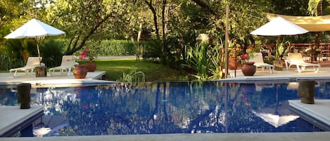 Una piscina al aire libre, sombrillas, tumbonas