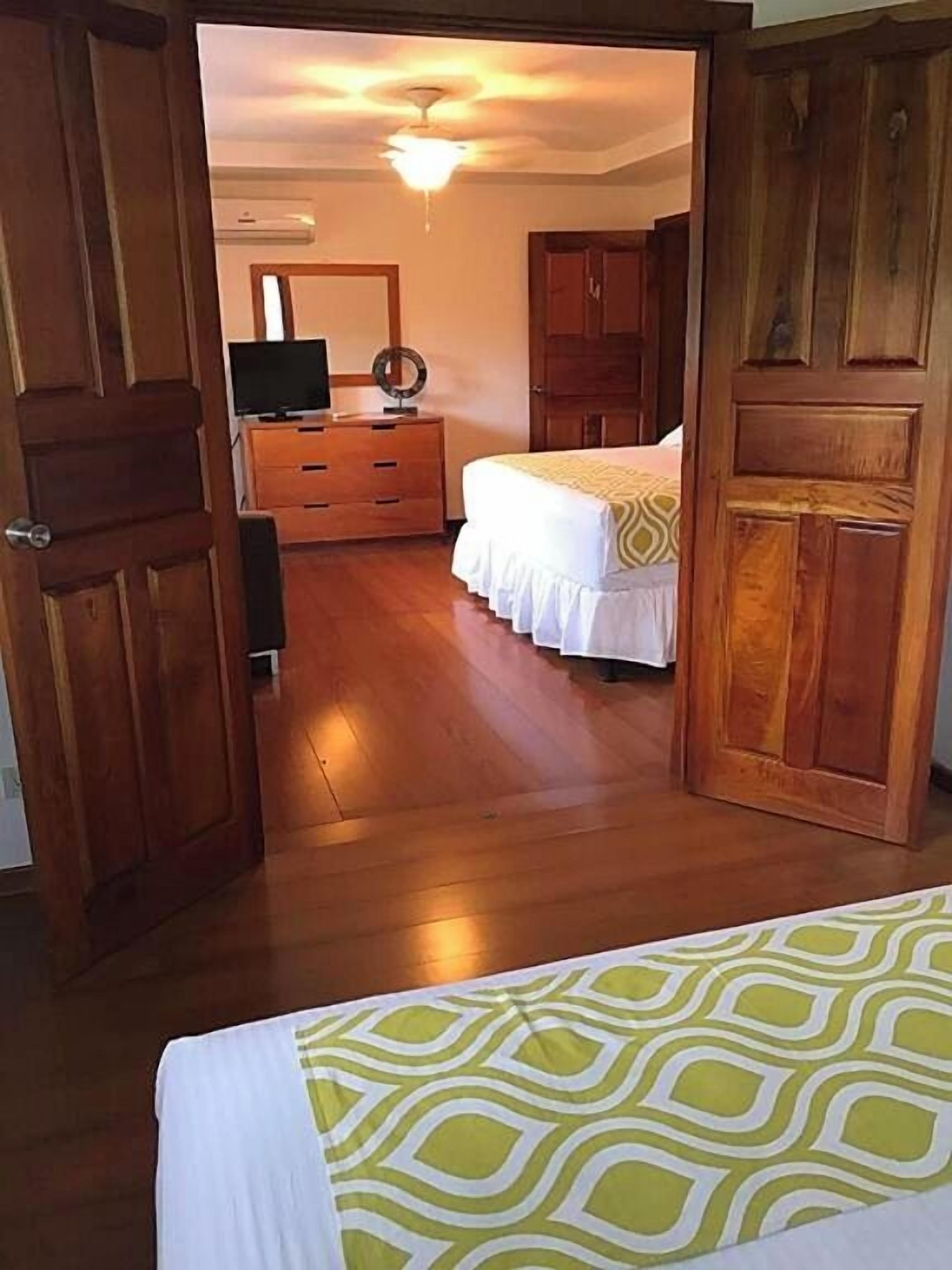 Un dormitorio con cama, armario de madera y cómoda.