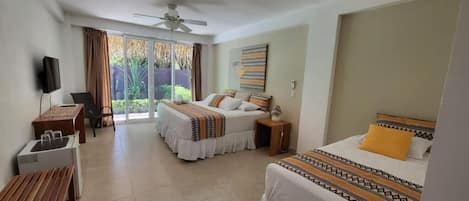 A hotel room with two beds, a desk with a chair, a TV, and a window with curtains.