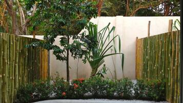 A garden with a concrete planter, bamboo fencing, and various shrubs and plants.