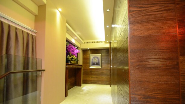 Un couloir avec un mur recouvert de panneaux de bois, une porte en verre et un tableau encadré accroché au mur.