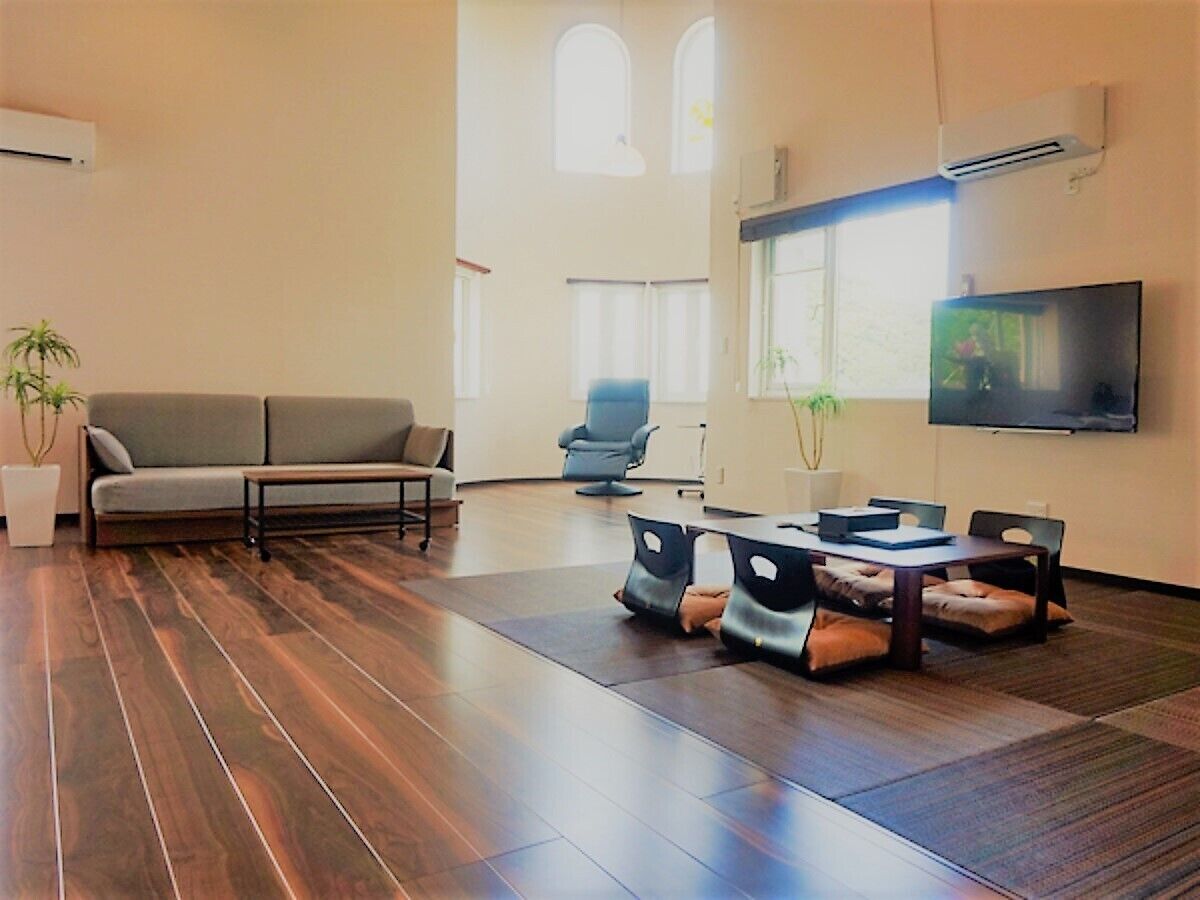 A modern living room with a sofa, chairs, a TV, and a table with laptops.