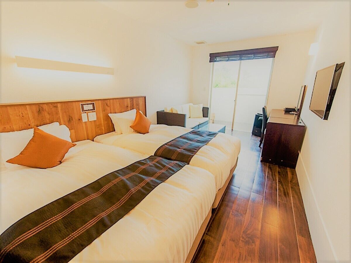 A hotel room with a large bed, a desk, a chair, and a window with a view.