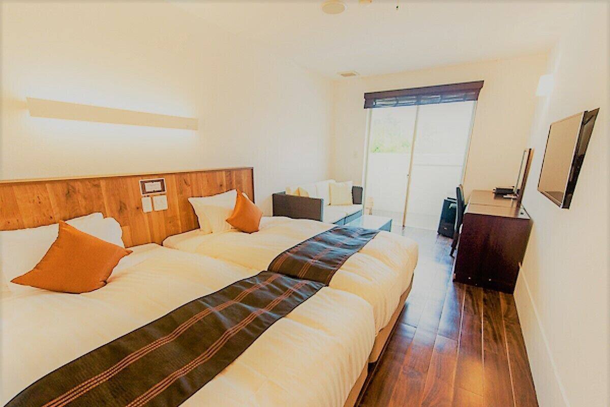 A hotel room with a large bed, a desk, a chair, and a window with a view.