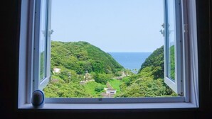 A window with a view of a lush green landscape and a body of water. - LiVEMAX RESORT Izu Shimoda (Shimoda)
