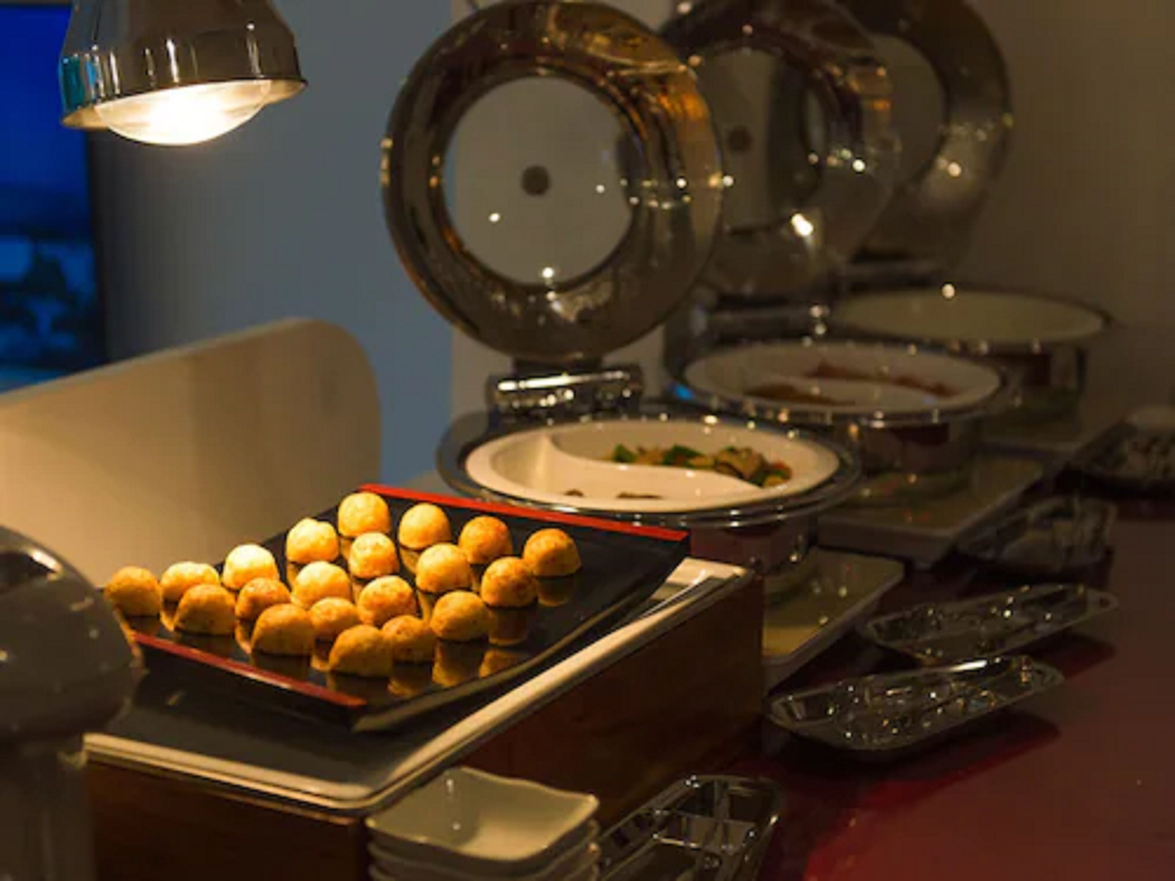 A buffet setup with various dishes and a tray of golden-brown pastries.