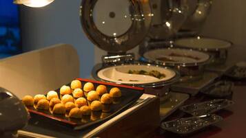 A buffet setup with various dishes and a tray of golden-brown pastries.