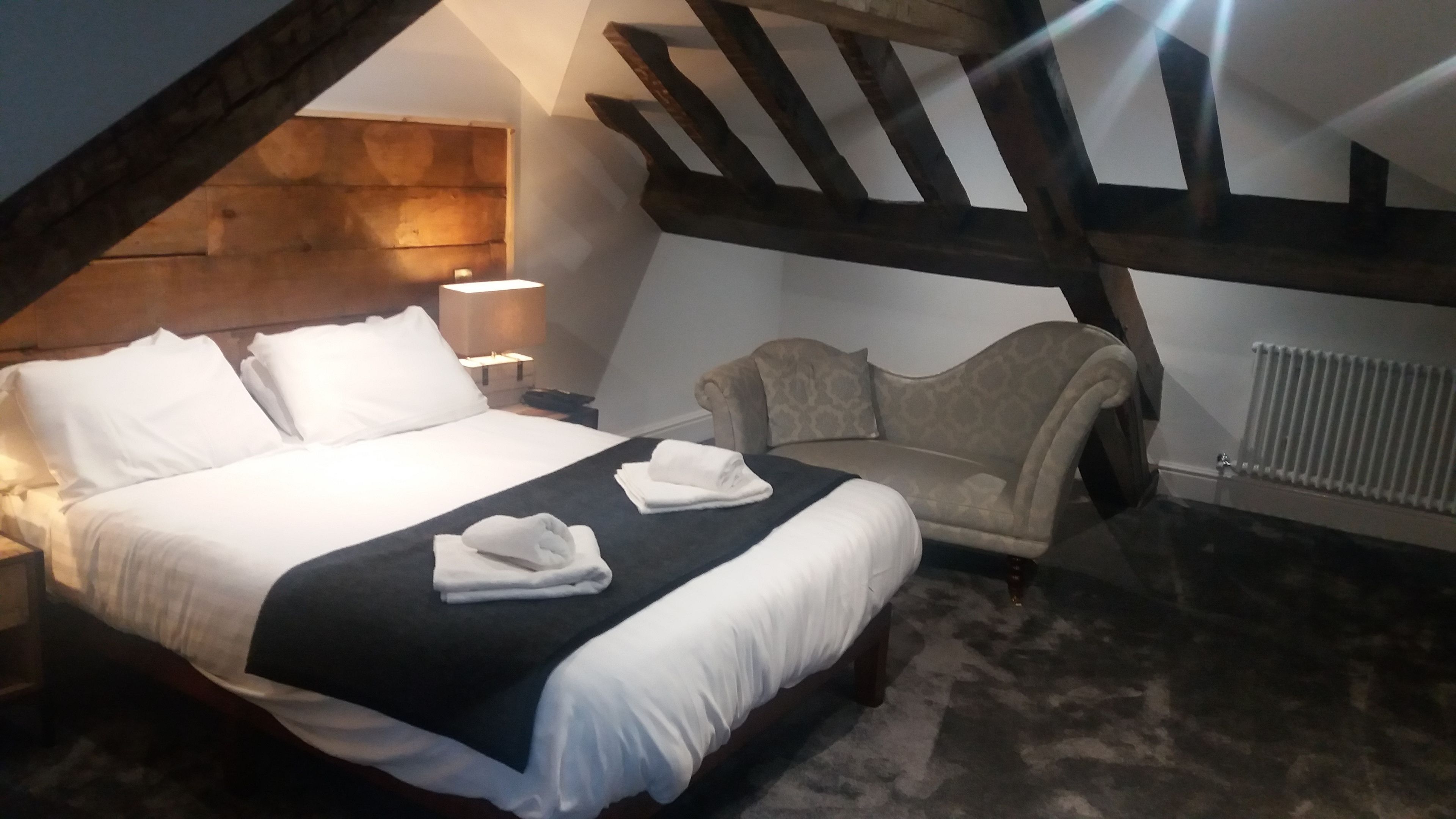 A bedroom with a bed, bedside lamps, a chair, and a radiator.