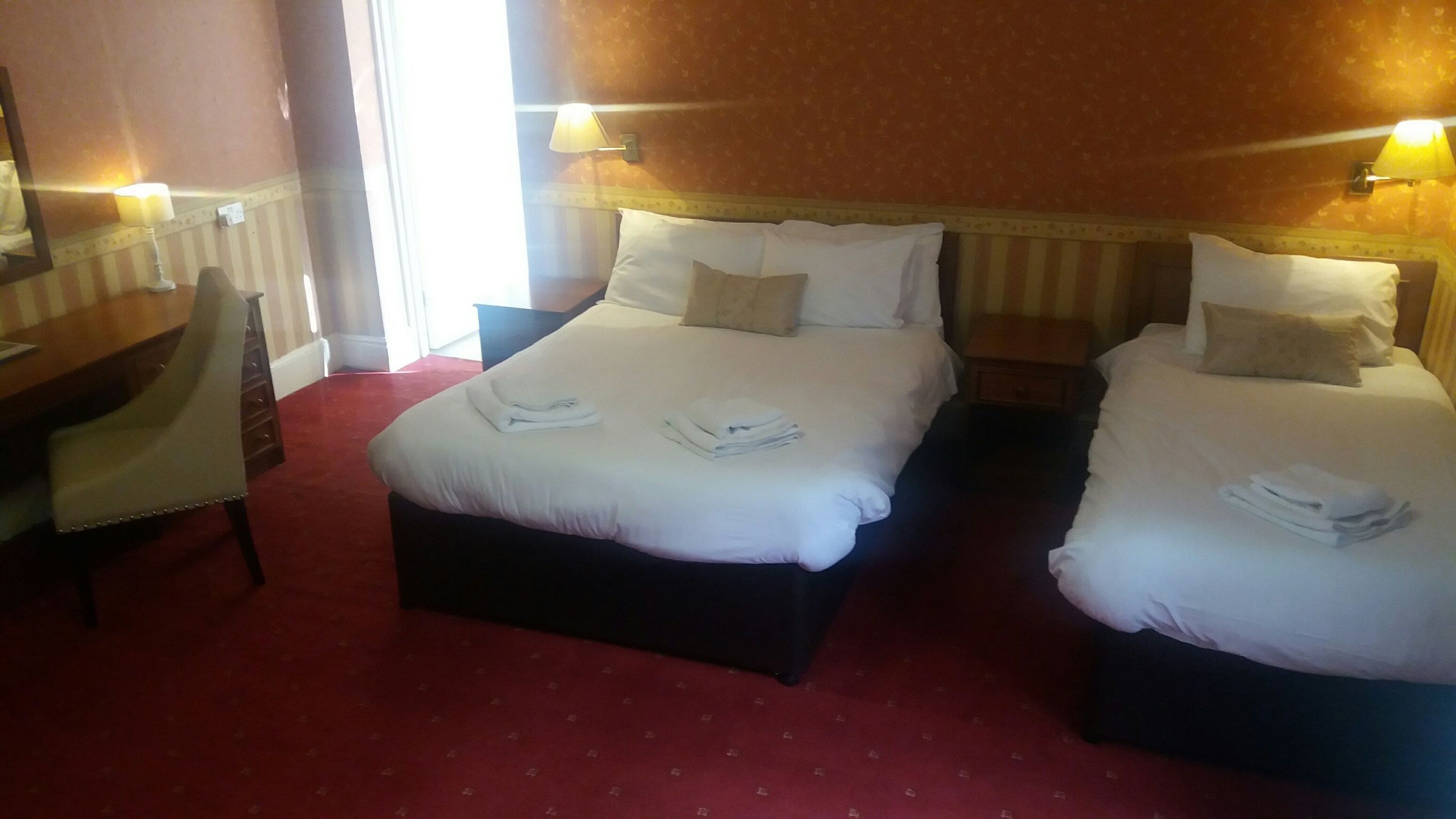 A hotel room with two beds, a desk, and a chair.