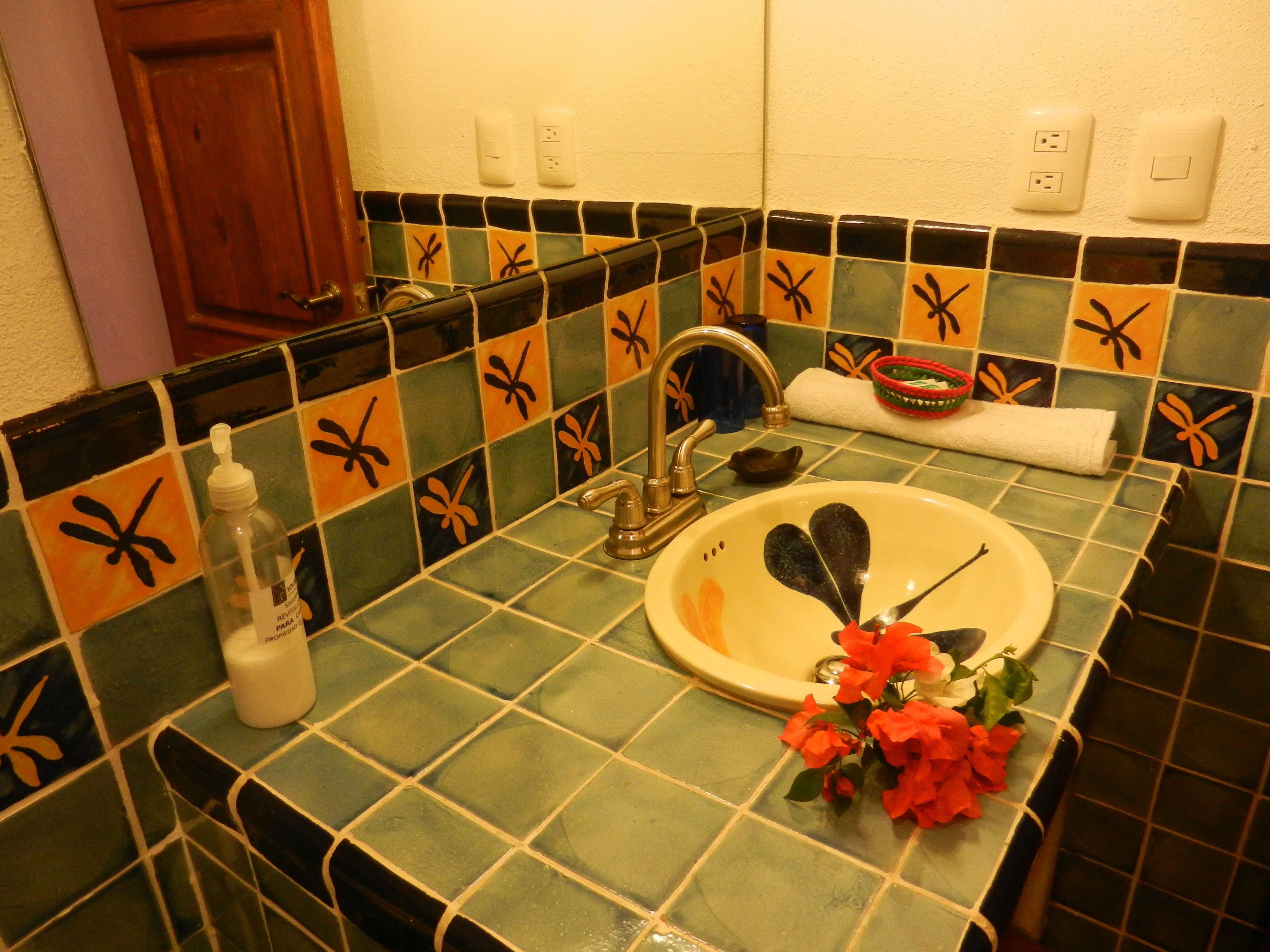 Un baño con lavamanos, grifo y azulejos decorativos.
