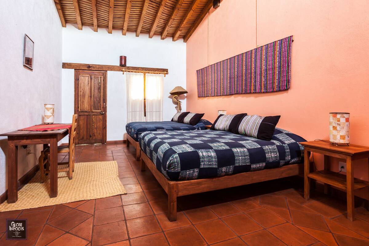A bedroom with a wooden bed, a desk, a chair, and a small table.