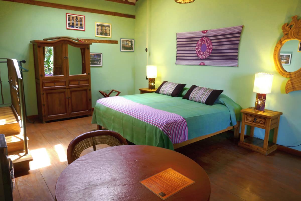 A bedroom with a bed, two bedside tables with lamps, a wooden wardrobe, a chair, and a table.