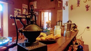 Una encimera de cocina con una cafetera francesa, un tarro de leche y pasteles.