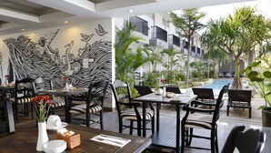 Un restaurant avec vue sur la piscine, décoré de motifs zébrés noir et blanc, doté d’une terrasse et d’un design moderne.
