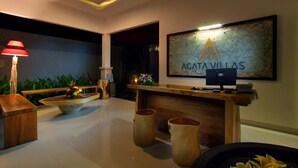 A reception area with a wooden desk, a red lamp, a framed sign, and a plant. - Agata Villas (Seminyak)