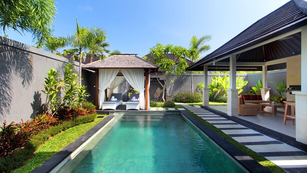 A swimming pool with a cabana, lounge chairs, and a covered seating area with a table and chairs. - Agata Villas (Seminyak)